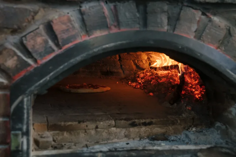 Pizza kako izlazi iz krušne peći na drva